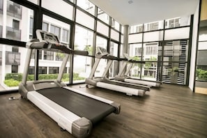 A gym with treadmills, large windows, and a modern interior. - Econest Apartment By The One - Educity Ecobotanic (Gelang Patah)