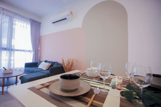 A dining area with a table set for two, a sofa, and a window with curtains.