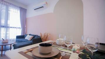 A dining area with a table set for two, a sofa, and a window with curtains.