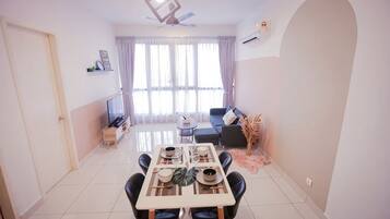 A dining area with a table, chairs, and a TV in the background.