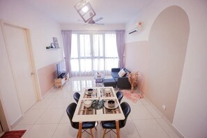 A dining area with a table, chairs, and a TV in the background.