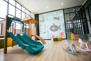 A children's play area with a slide, climbing structure, and rocking chairs. - Econest Apartment By The One - Educity Ecobotanic (Gelang Patah)