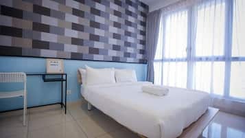 Quarto de hotel com uma cama grande, mesa de cabeceira, uma cadeira e vista para o exterior pela janela.