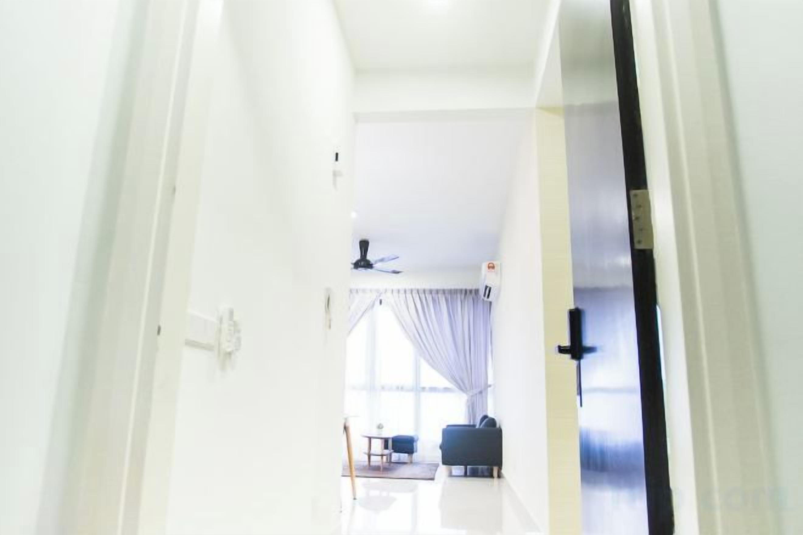 A hallway leading to a living area with a ceiling fan, a sofa, and a window with curtains.