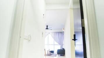 A hallway leading to a living area with a ceiling fan, a sofa, and a window with curtains.