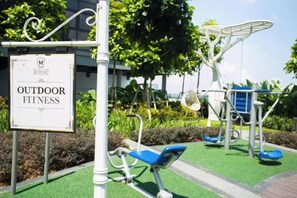 An outdoor fitness area with exercise equipment and a sign indicating the location.