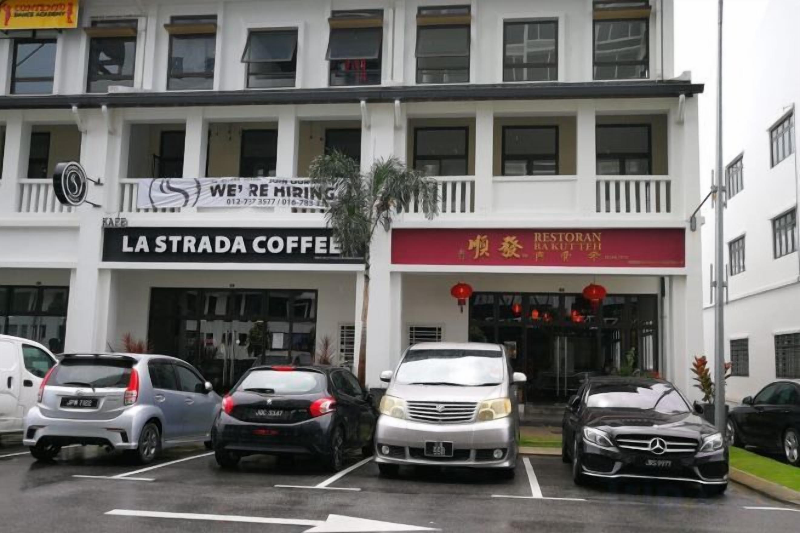 A building with multiple businesses including a coffee shop and a restaurant. There are several cars parked in front.