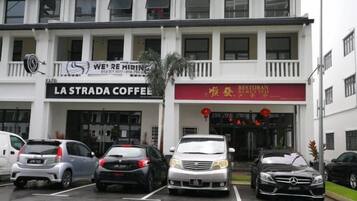 A building with multiple businesses including a coffee shop and a restaurant. There are several cars parked in front.