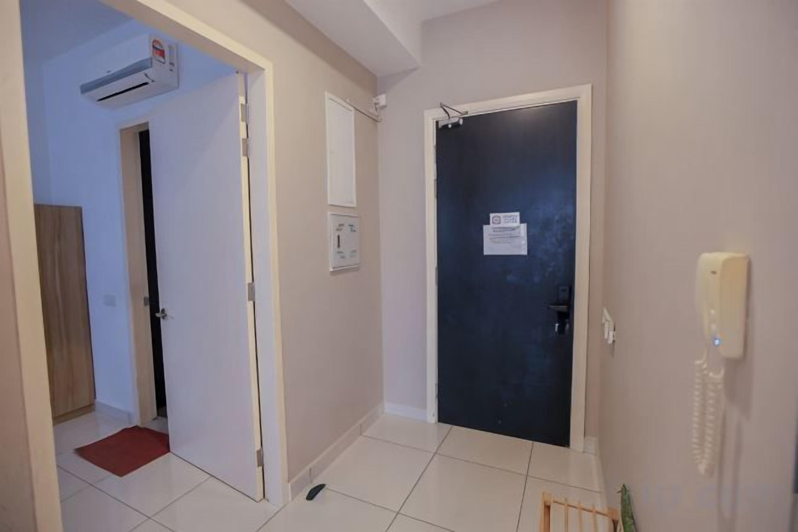 A hallway with a closed door, a phone, and a red mat leading to a room.