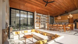 A modern interior with a wooden ceiling, large windows, a dining area, and a kitchen. - Villa Serai 5br to the beach (Bali)