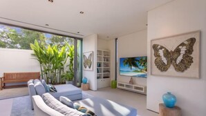 Un salón moderno con un sofá gris, un banco de madera y un ventanal grande.
