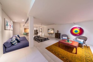 Un saló modern amb un conjunt de sofàs, una taula de centre i una obra d'art colorida a la paret.