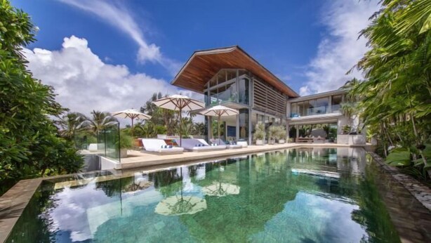 Un hotel moderno con piscina, tumbonas y sombrillas.