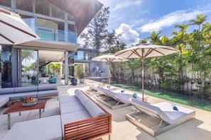 A modern outdoor living area with a pool, lounge chairs, and umbrellas. - Sava Villa 7 Villa Aqua (Takua Thung)
