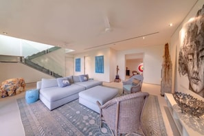 A modern living room with a sectional sofa, a patterned rug, and a staircase. - Sava Villa 7 Villa Aqua (Takua Thung)