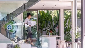 Un interior moderno con una escalera de cristal, un comedor y una cocina.