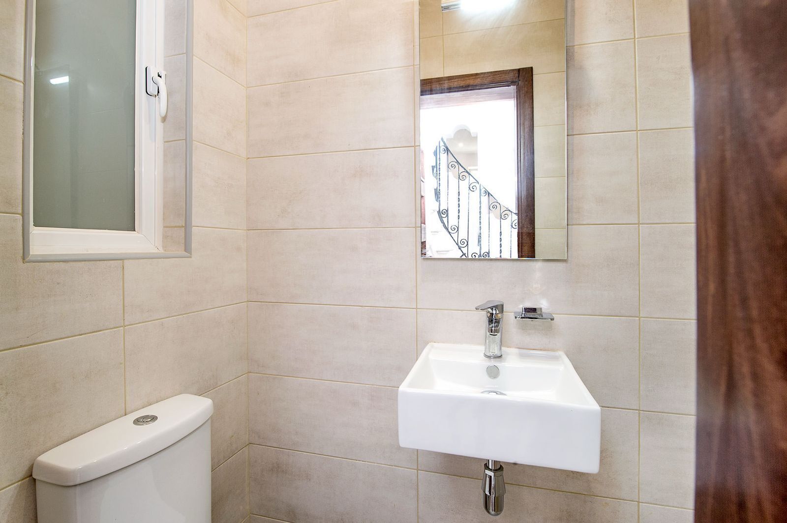 A bathroom with a white sink, a toilet, and a mirror.