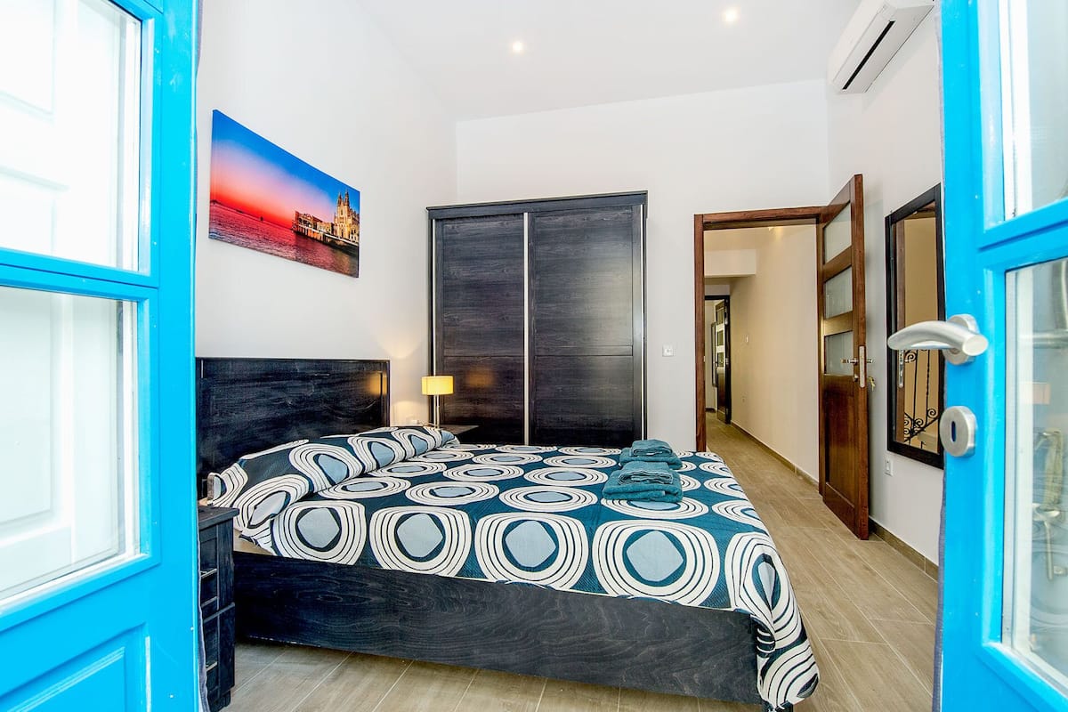 Une chambre à coucher avec un lit, une armoire, un tableau et une porte.