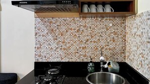 Una cocina moderna con estufa a gas, pileta de acero inoxidable y un salpicadero decorativo.
