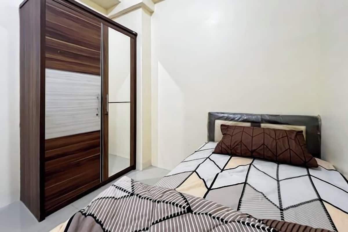 Un dormitorio con cama, armario y cabecera.