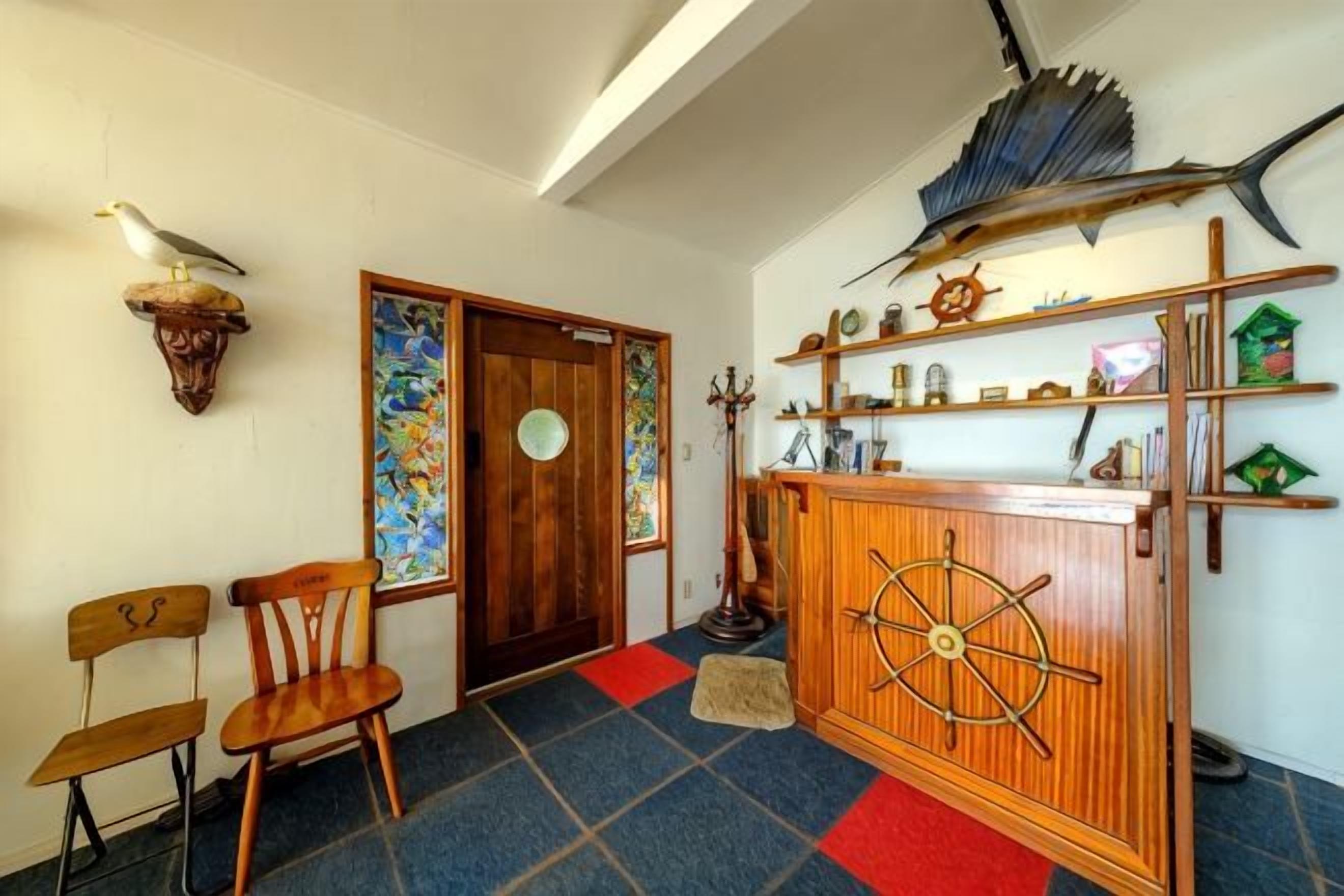 A room with a wooden desk, chairs, a decorative wall, and a large fish mounted on the wall.