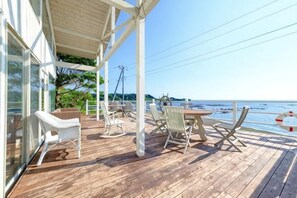 A wooden deck with outdoor furniture, a covered area, and a view of the sea. - Miura Bambino (Miura)