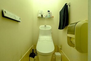 Un baño pequeño con inodoro, lavamanos y secamanos.