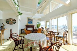 Comedor con una mesa redonda, sillas y vista al mar a través de amplios ventanales.