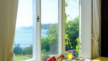 A room with a large window overlooking a body of water and greenery.