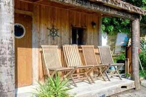 A wooden cabin with a porch, two wooden chairs, and a small door. - Miura Bambino (Miura)