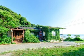 A small house with a porch, surrounded by lush greenery and a clear view of the sea. - Miura Bambino (Miura)
