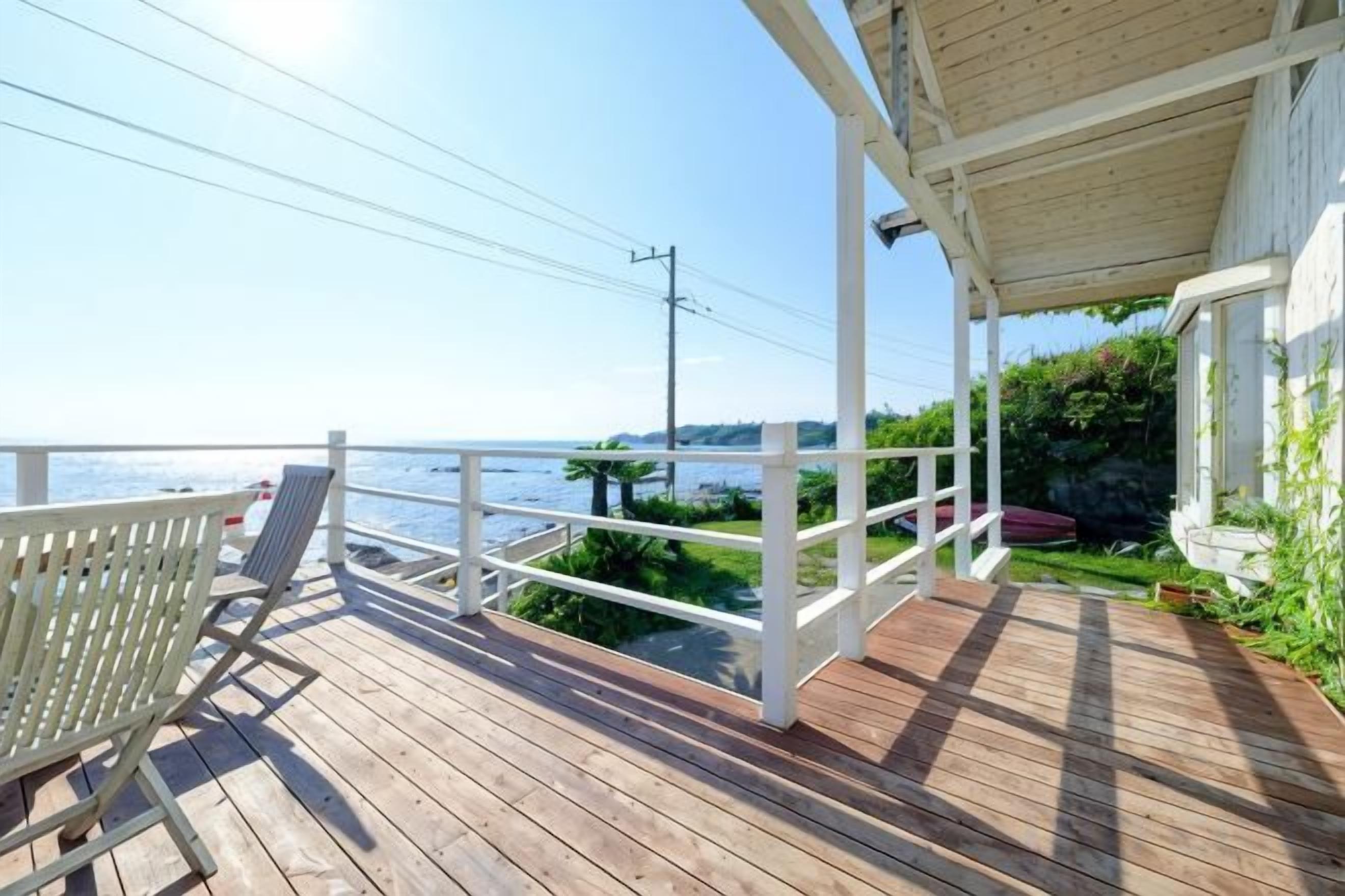 A wooden deck with a white railing, overlooking a body of water.