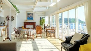 Tilava huone, jossa on ruokailutila, takka ja suuret ikkunat, joista avautuu näkymä ulos.