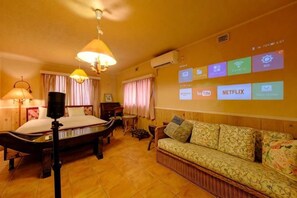 Une chambre d’hôtel équipée d’un lit, d’un canapé, d’un bureau et d’un téléviseur fixé au mur, qui diffuse différentes chaînes.
