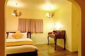 Une chambre d’hôtel avec un lit, un bureau et deux lampes fixées au mur.