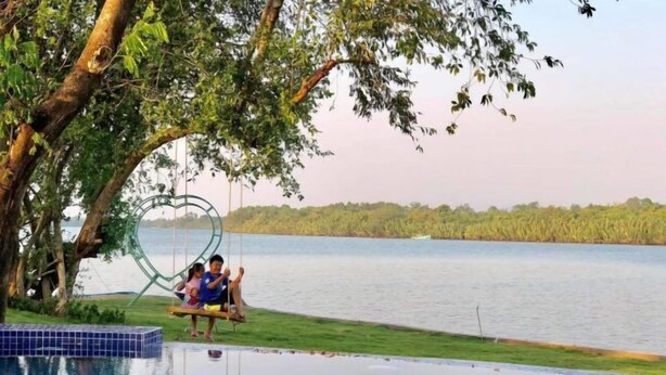 A pool area with a heart-shaped structure, a tree, and a view of a lake. - Moly Resort (Kampot)