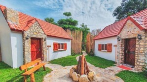 A courtyard with stone buildings, wooden benches, and a central fire pit. - Moly Resort (Kampot)