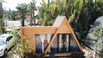 A small, triangular wooden structure with a sloped roof, large windows, and a door.