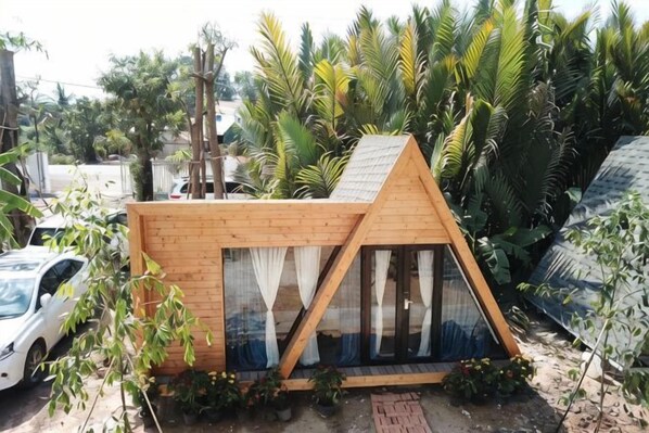 A small, triangular wooden structure with a sloped roof, large windows, and a door.