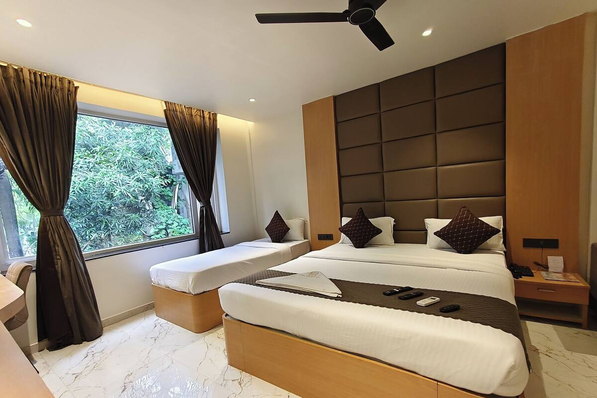 A modern hotel room with a large bed, a bedside table, a nightstand, and a ceiling fan.
