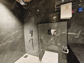 Un baño moderno con cabina de ducha de vidrio, inodoro blanco y pared revestida de mármol.