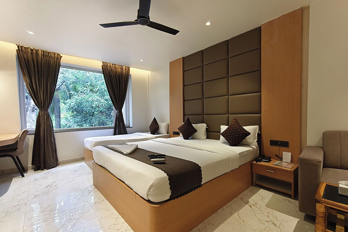 A modern hotel room with a large bed, a desk, a chair, a nightstand, and a ceiling fan.