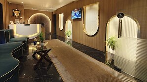 Un área de recepción moderna con mostrador, asientos y una pantalla de televisión.