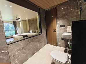 A modern bathroom with a large mirror, a toilet, and a sink. - The Golden Arc (Pune)
