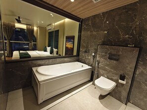 Un baño moderno con una bañera grande, zona de ducha separada y un inodoro.