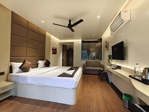 A modern hotel room with a large bed, a sofa, a TV, and a desk. - The Golden Arc (Pune)
