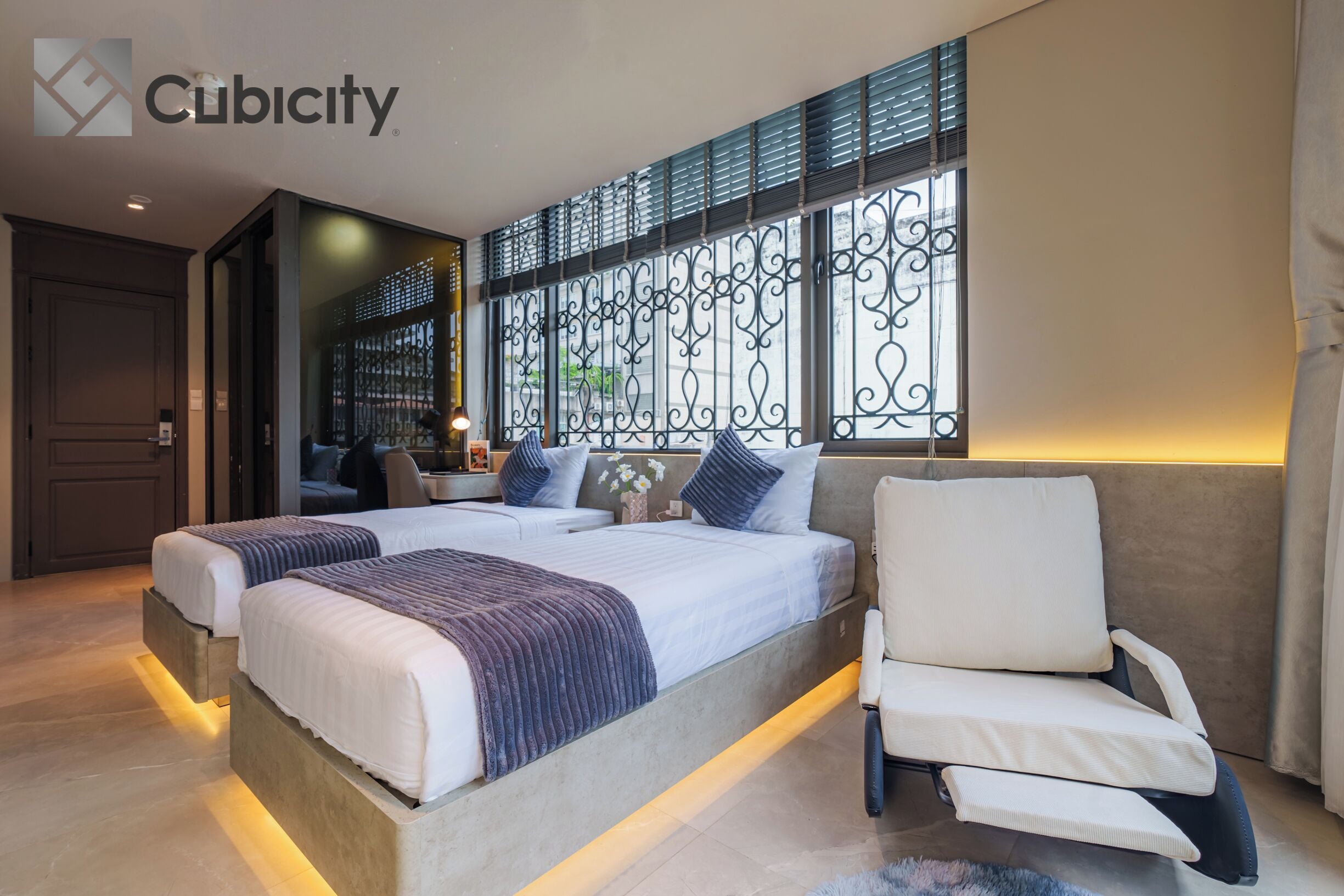 A modern bedroom with two beds, a sofa, and a decorative window with metalwork.