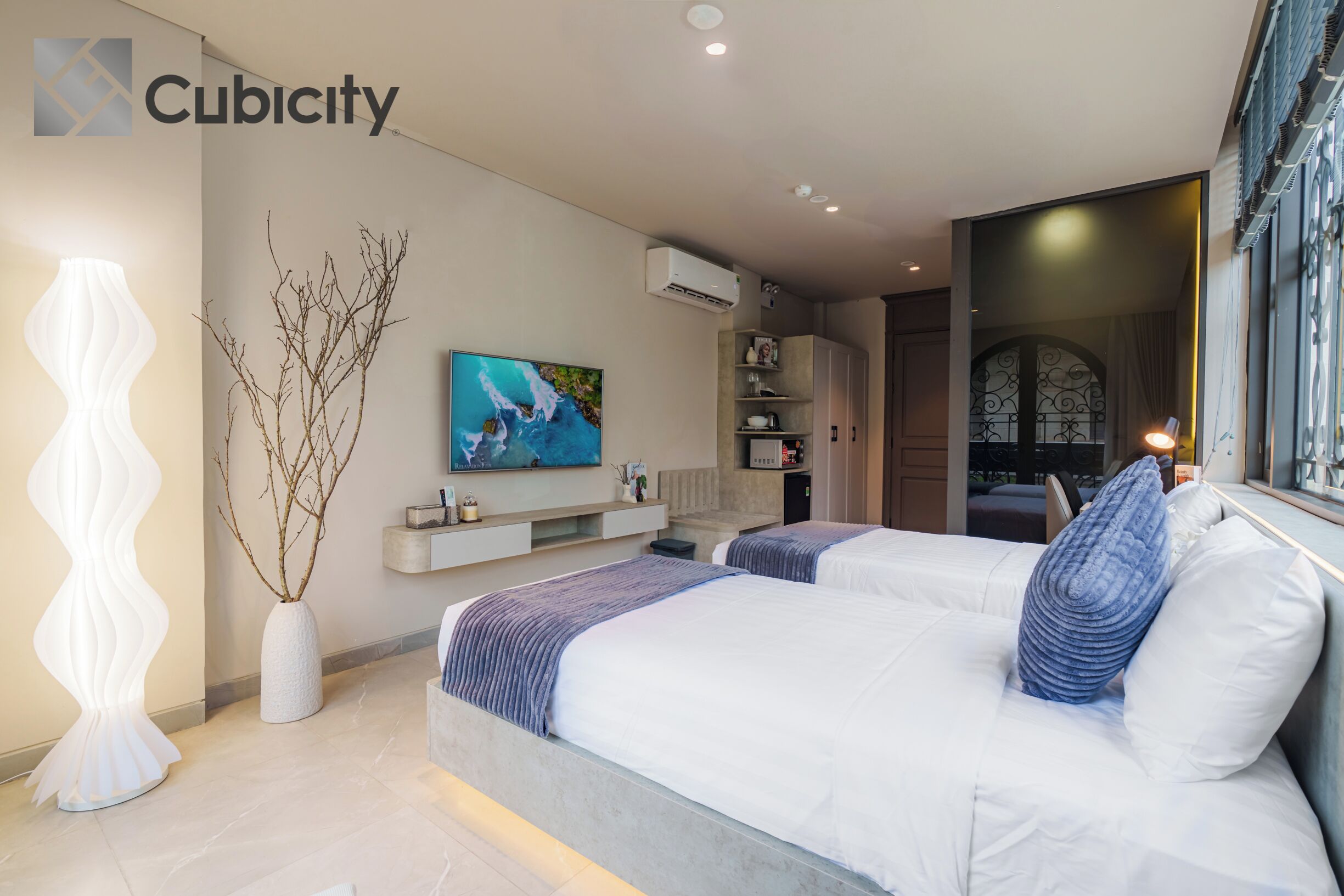 A modern bedroom with two beds, a mounted TV, and a decorative vase.