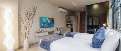 A modern bedroom with two beds, a mounted TV, and a decorative vase.