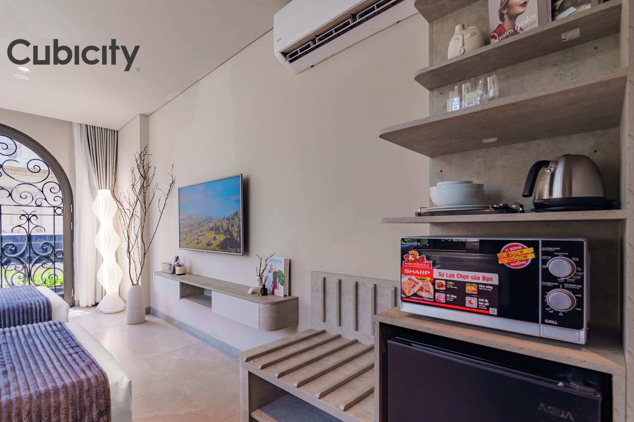 A modern hotel room with a bed, a TV, a microwave, and a refrigerator.